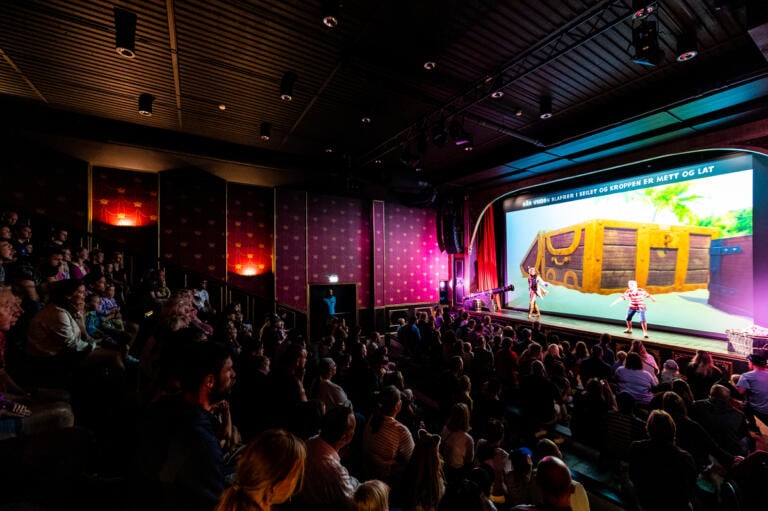 mørklagt sal med publikummere og Pinky og Rosa på scenen